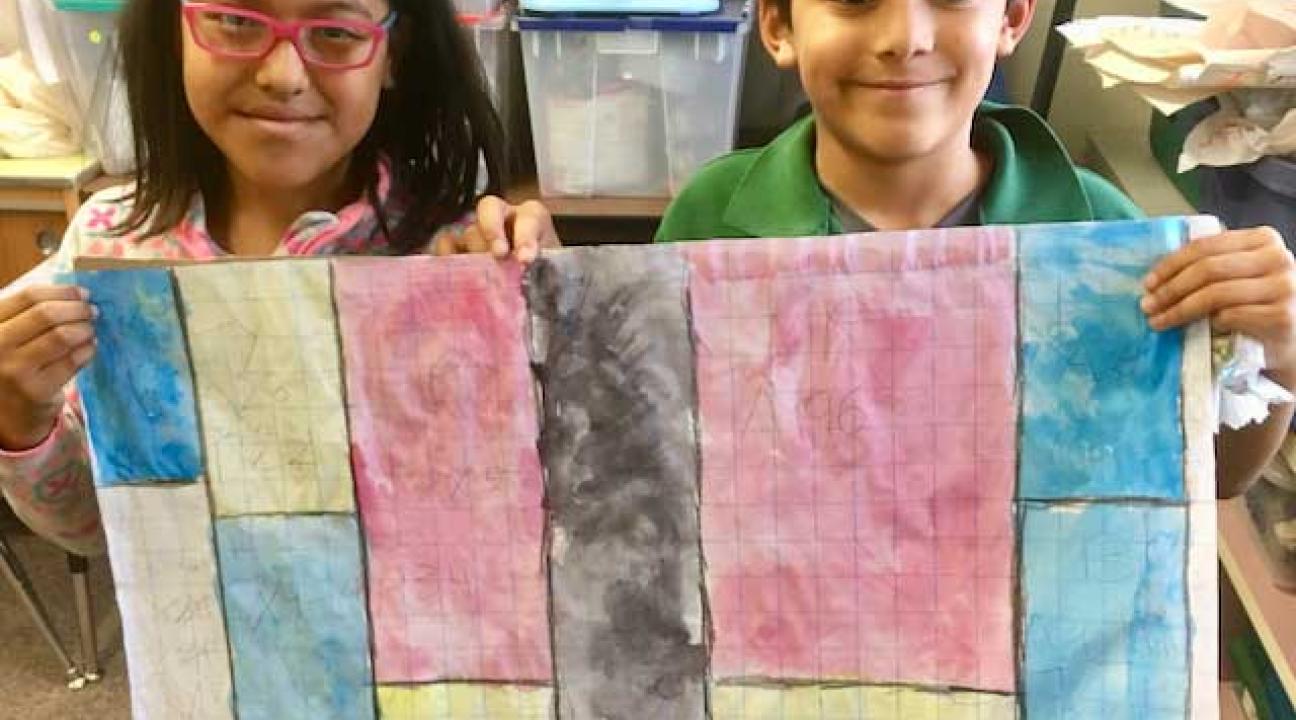 Two children holding a large  paper that has vertical colored bars.