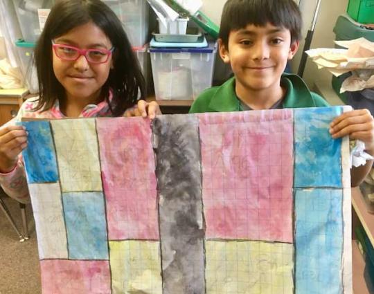 Two children holding a large  paper that has vertical colored bars.