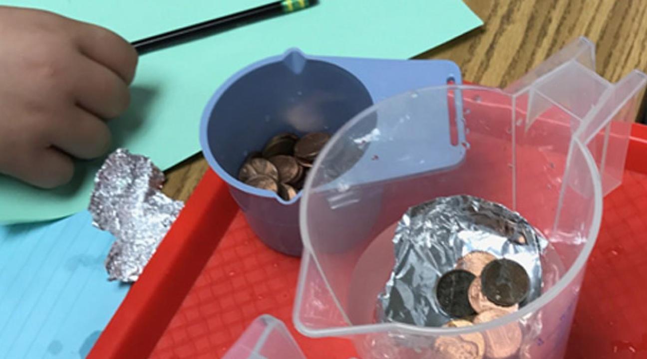 Cup of coins next to a pitcher of water with foil and coins floating inside.