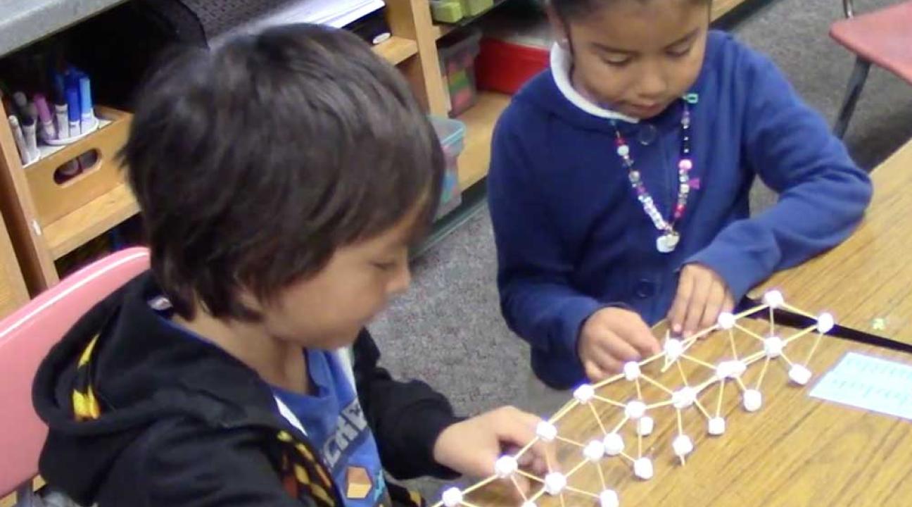 2 children woking on a bridge made of sticks.
