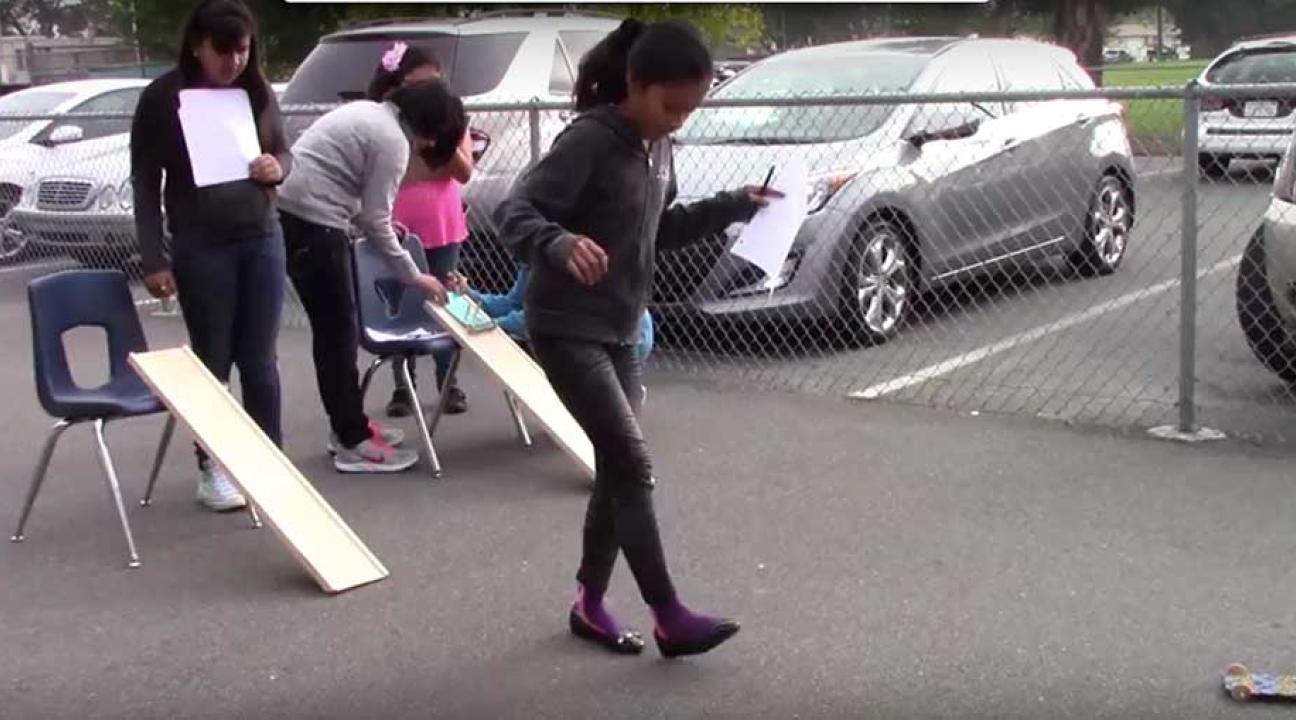 Young child measuring the distance of a toy car travel.