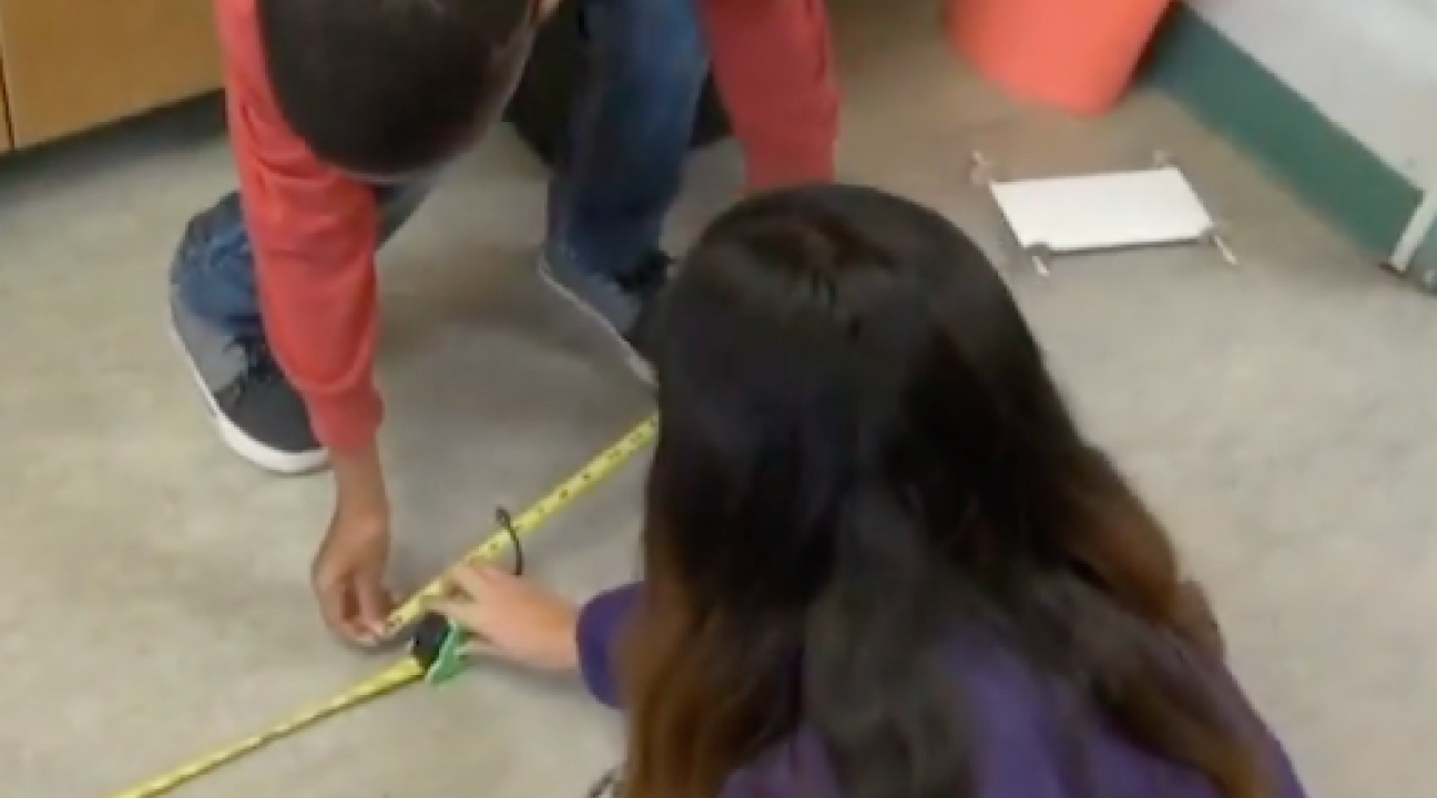2 children using a tape measure.
