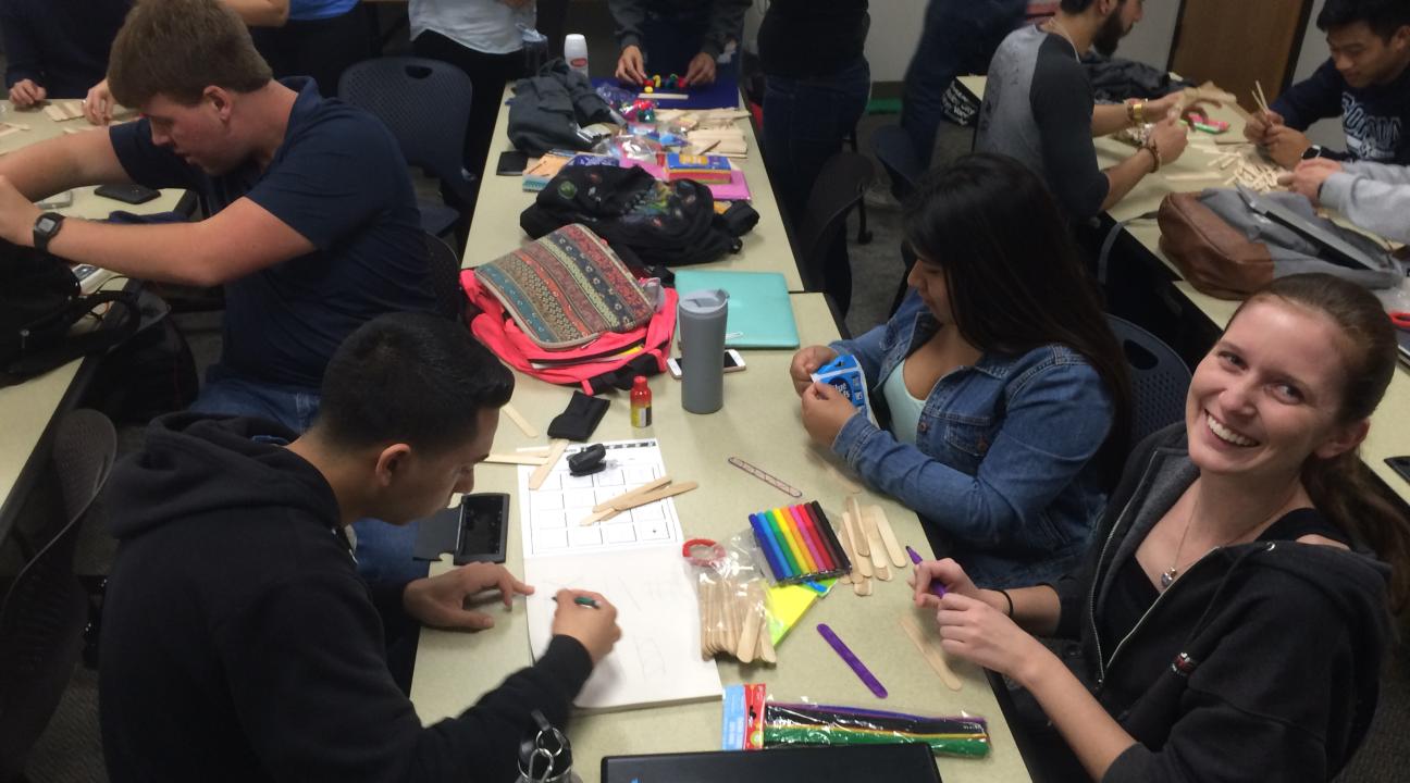 Students at a table, one student is looking up at the camera