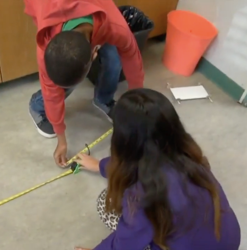 2 children using a tape measure.