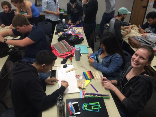 Students at a table, one student is looking up at the camera